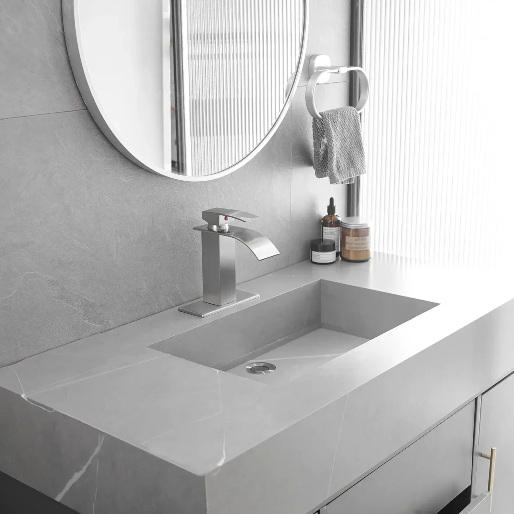 Silver waterfall bathroom faucet installed on a gray bathroom vanity sink